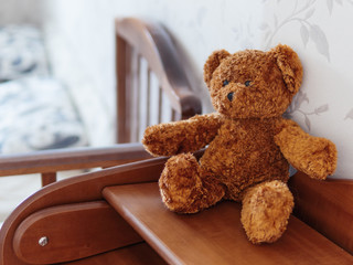 Teddy bear on wooden dresser. Plush toy in kids room.
