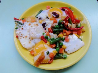 eggs benedict with vegetables on a yellow plate