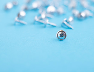 Many blurred screws on metal table, soft focus