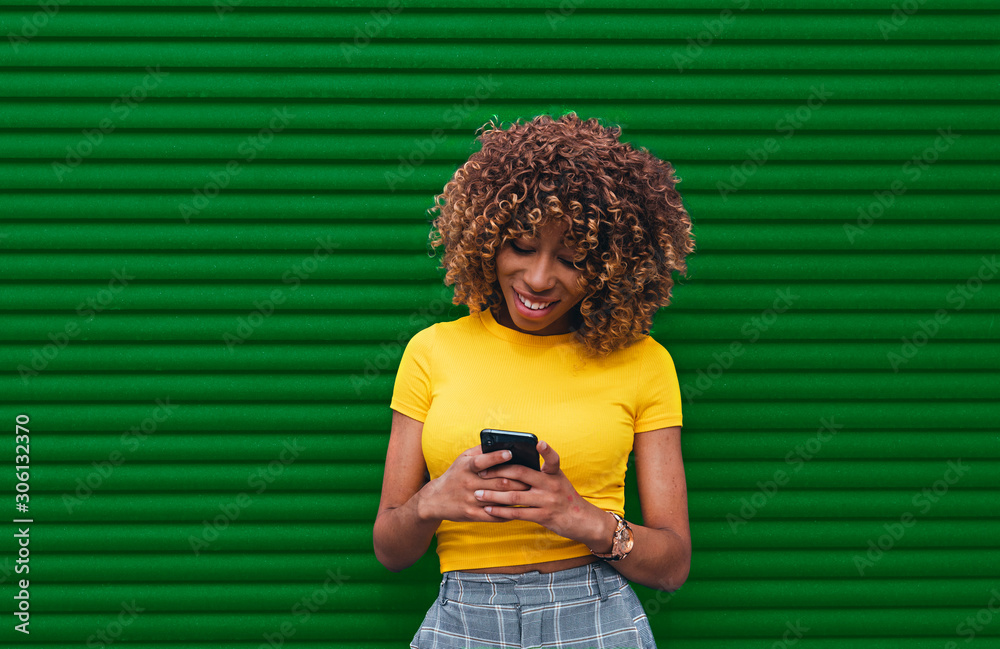 Wall mural young woman in a yellow blouse holding de phone with both hands