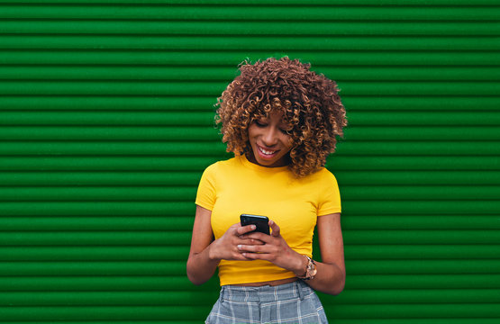 Young woman in a yellow blouse holding de phone with both hands
