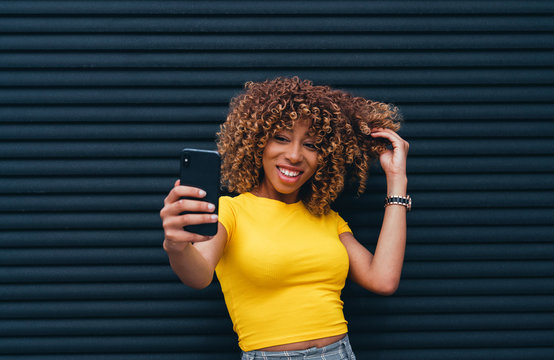Young woman taking a selfie showing off her fantastic curly hair.