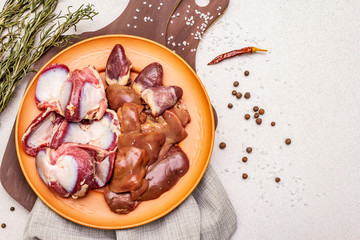 Fresh raw duck offal: heart, liver, stomach. Dry spices, salt, chili pepper. Wooden cutting boards, stone concrete background