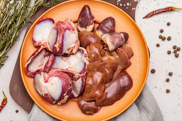 Fresh raw duck offal: heart, liver, stomach. Dry spices, salt, chili pepper. Wooden cutting boards, stone concrete background