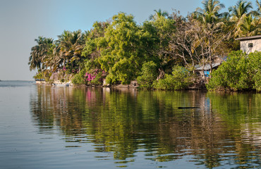 Fototapeta na wymiar Very Beautiful and scenic view of typical South Indian Coastal Village, wherein an island full of natural vegetation during spring, and its reflection visible in calm water. Sea can be seen at horizon