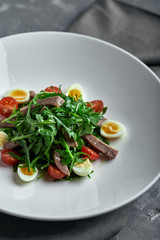 Tasty italian salad of beef tongue with eggs, arugula, tomato, spices and sauce