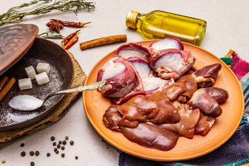 Fresh raw duck offal: heart, liver, stomach. Dry spices, salt, sugar, oil. Frying pan, stone concrete background