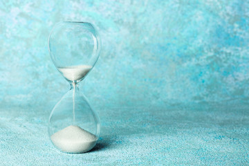 An hourglass on a teal blue background with a place for text. Time management or pressure concept...