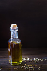 Hemp oil in a glass bottle and seeds on a dark wooden background. Vertical photo.