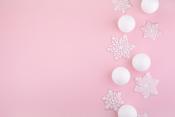 frame made of white christmas decoration with christmas glass balls on pink background. flat lay, top view