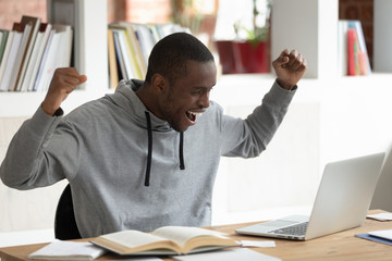 Overjoyed young african american male student celebrating good exam results.