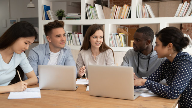 Happy female team leader sharing knowledge with diverse university friends.