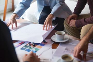 Interior designer presenting blueprint and discussing renovation project with clients. Closeup of...