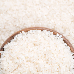Raw white polished milled edible rice crop on white background in brown bowl, organic agriculture design concept. Staple food of Asia, close up.