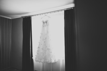 The perfect wedding dress with a full skirt on a hanger in the room of the bride