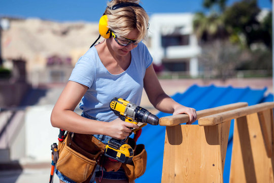 Handy woman with toolsbelt and yellow drill in her hands