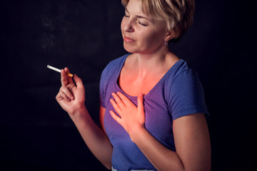 Woman smokes cigarette and has problem with lungs or heart attack.