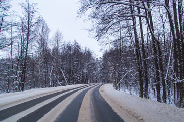Asphalt road in the forest covered with snow