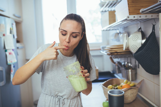 Woman Tasting Smoothie In Kitchen