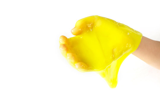 Modern toy called slime. Child playing transparent yellow slime. Hand holding a mucus on a white background.