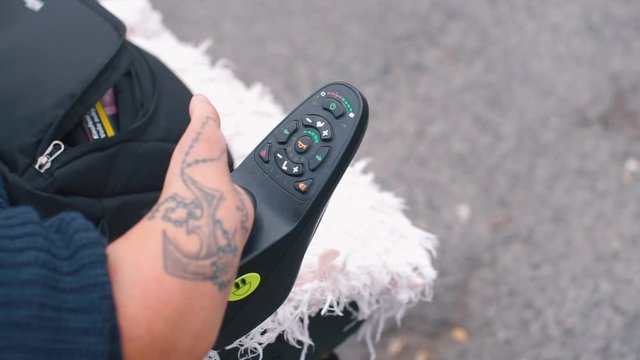 Close-up of hand of disabled person and wheelchair joystick.