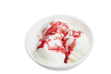 balls of white ice cream with red berry syrup in a white bowl on a white background. Top view