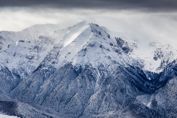 Beautiful mountain panorama in winter with fog and clouds. Bucegi mountains seen from Postavaru,...