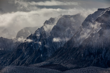 Beautiful mountain panorama in winter with fog and clouds. Bucegi mountains seen from Postavaru, Romania.