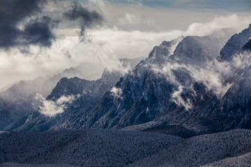 Beautiful mountain panorama in winter with fog and clouds. Bucegi mountains seen from Postavaru, Romania.