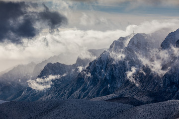 Beautiful mountain panorama in winter with fog and clouds. Bucegi mountains seen from Postavaru, Romania.