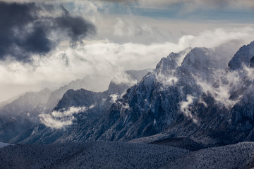 Beautiful mountain panorama in winter with fog and clouds. Bucegi mountains seen from Postavaru, Romania.