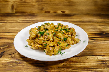 Stewed mushrooms with sour cream on wooden table