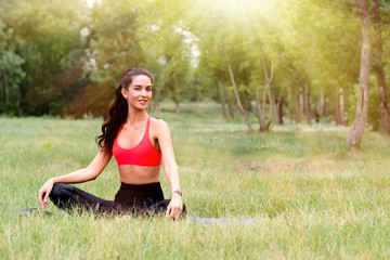 Young attractive smiling toned brunette woman doing yoga outside in a park. Healthy lifestyle concept