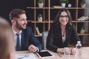 selective focus of young businessman and businesswoman smiling at business meeting