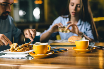 close up of coffee in yellow mug, blurred people eating in background