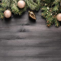 Natural green pine tree with golden baubles and decor on black wooden background, copy space, top view. Christmas border with ornaments and fir tree, flat lay