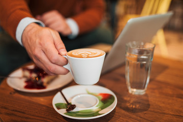Businessman having cup of coffee in a cafe, close-up