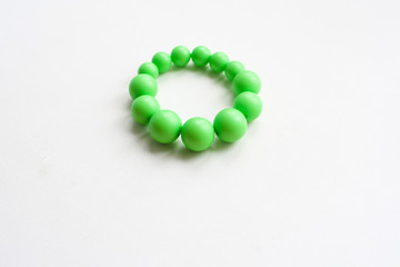 Green bracelet of round beads of different sizes on a white background