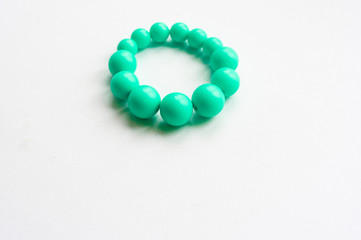 Turquoise color bracelet of round beads of different sizes on a white background, copy space