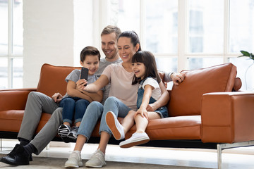 Happy young family have fun using smartphone together