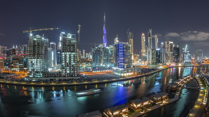 Fototapeta premium Night city Dubai near canal with bright skyscrapers aerial timelapse