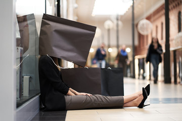 Concept sales. Black friday. Woman with paper shopping bag on her head tired after shopping.