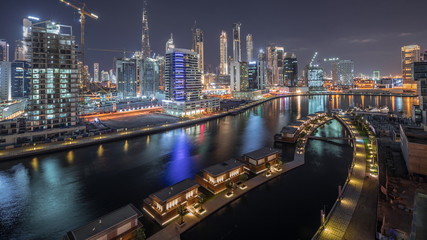 Fototapeta na wymiar The rhythm of the city of Dubai near canal at night aerial timelapse