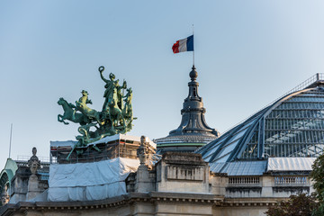 Fototapeta premium French National Flag and statue on The Grand Palais in Paris, currently the largest existing ironwork and glass structure in the world