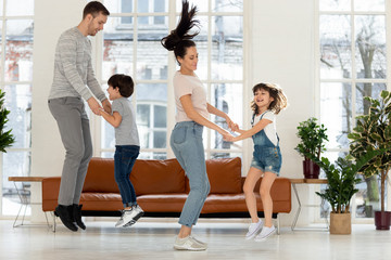 Fototapeta premium Playful parents have fun jumping playing with little kids