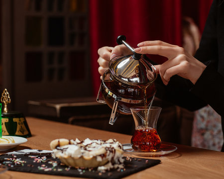 A Person Pouring Black Tea Into Armudu Glass