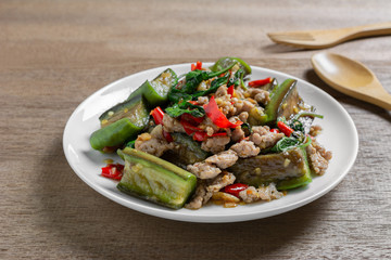 close up of stir fried eggplant with pork in a ceramic dish on wooden table. asian homemade style food concept.