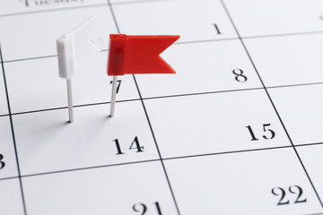 Red pin on a date on a calendar closeup. Important date. Place for text. Planning concept.