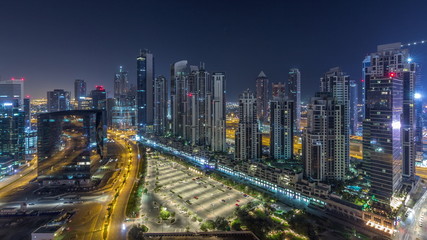 Modern residential and office complex with many towers aerial night timelapse at Business Bay, Dubai, UAE.