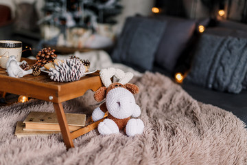 Table with a cup on the bed, marshmallow and Christmas cookies, cozy knitted blanket. New Year 2019, flat lay. Christmas composition with a cup, tray, a deer and a mug. The background is blurred.